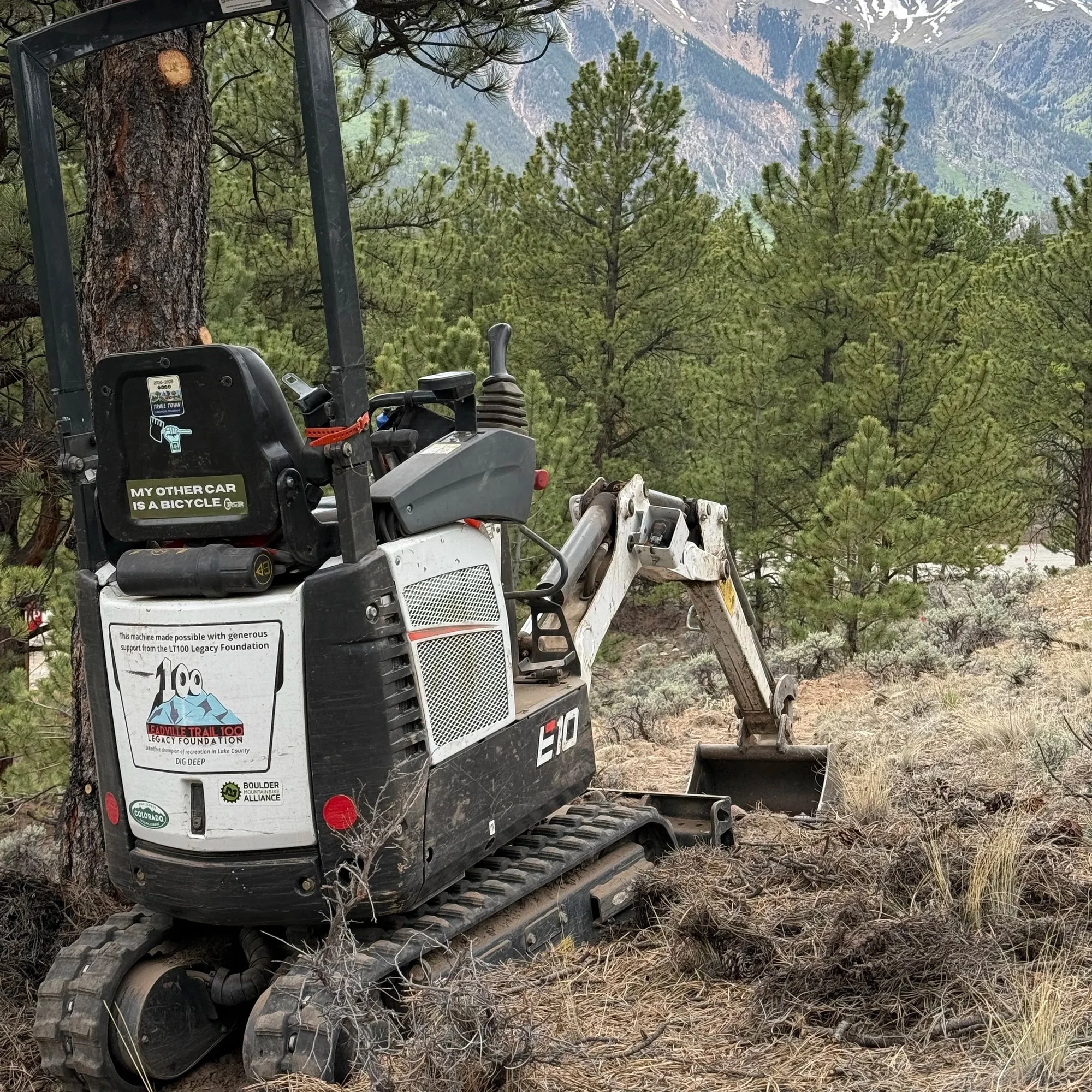 Mini-excavator used for trail work in a mountain landscape